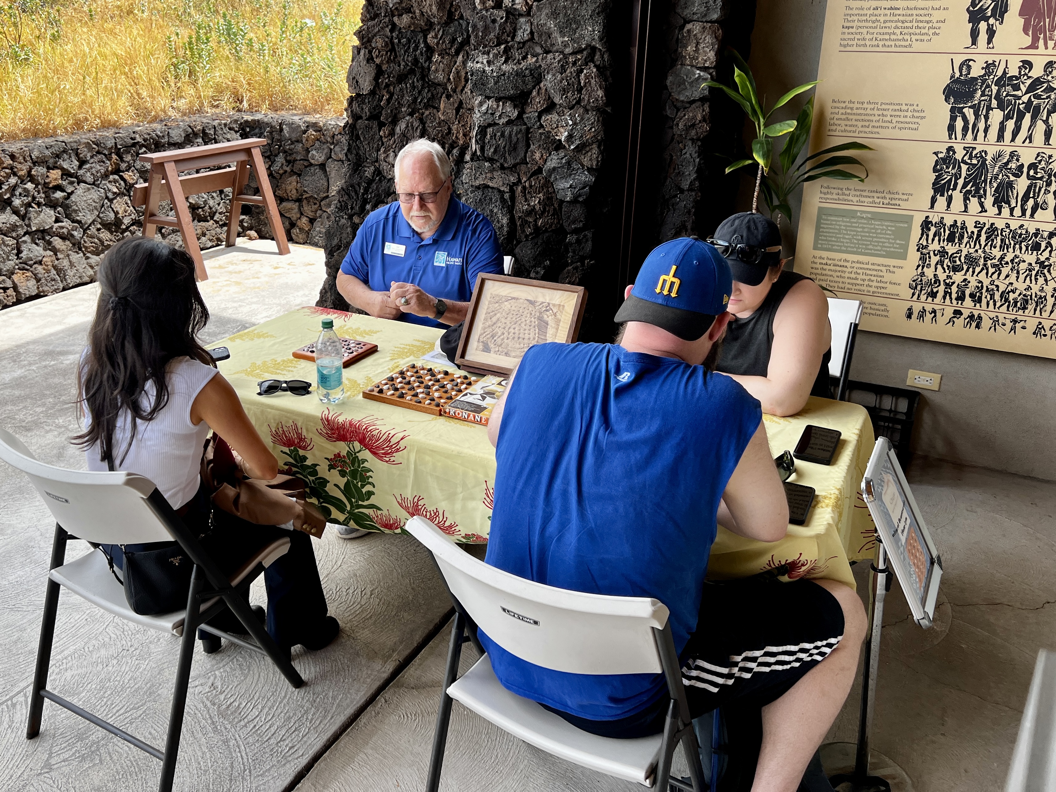 Ed Dowling sits at a table with a kōnane boards and players in front of him at PUHE.