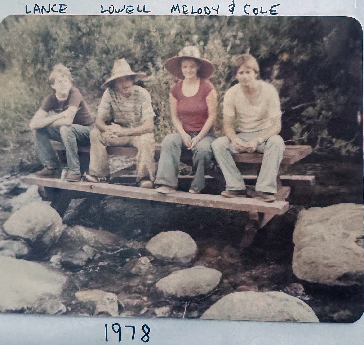 Mel Boehl and her family sit on a picnic table on boulders in a stream in a national park.